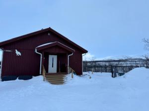 基尔匹斯扎我维Riekko Mökki的前面的红色谷仓,地面上有雪