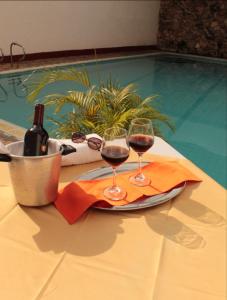 内瓦HOTEL DINASTIA REAL NEIVA的游泳池畔的桌子上放两杯葡萄酒