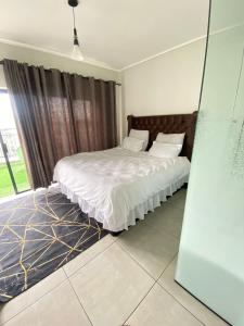 约翰内斯堡M O S Luxury Apartment的一间卧室配有一张带白色床单的床和一扇窗户。