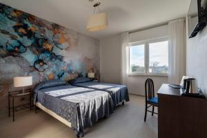 威尼斯丽都索瑞索酒店的卧室配有一张床,墙上挂有绘画作品