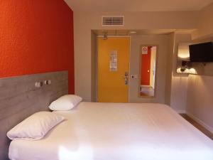 Yffiniac伊菲尼阿克圣布里厄宜必思快捷酒店的卧室配有一张白色大床和黄色门