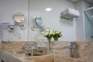 伊塔佩马Sofistic Hotel的浴室水槽,花瓶和镜子