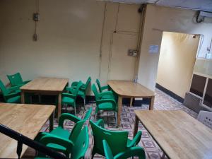 吉布提Addis Guest House Djibouti的一个配有书桌和绿色椅子的空教室