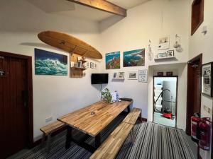 森嫩Lands End Hostel and B&B的一间设有木桌和冲浪板的墙壁客房