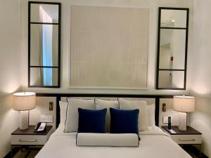 纽约纽约狄伦酒店的卧室配有一张白色床、两盏灯和两面镜子