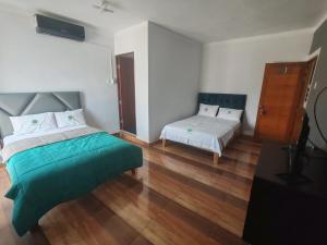 YurimaguasHOTEL EL TREBOL的一间卧室配有一张床、一张床和一张小床。