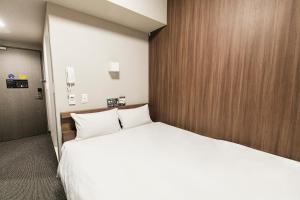 福冈博多微笑酒店的卧室设有白色大床和木墙