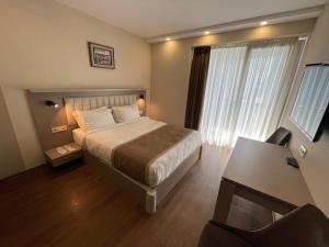 巴统Poseidon Apartments Batumi的一间卧室配有一张床、一张书桌和一个窗户。