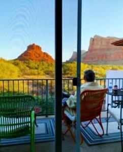 塞多纳Cozy Cactus Resort sorta-kinda的坐在阳台上的椅子上,望向峡谷的男人