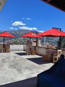 瓦拉斯Amazing Huaraz的一个带红色遮阳伞和桌椅的庭院