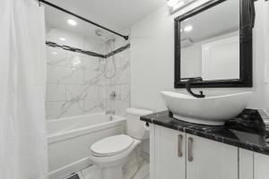 渥太华Modern 3BR Suites的白色的浴室设有水槽、卫生间和浴缸。