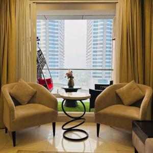 伊斯兰堡Elysium Tower Retreat Luxury Living Opposite Centaurus Mall - Islamabad的客厅设有两把椅子、一张桌子和大窗户