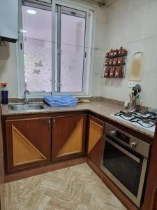 拉巴特Authentic moroccan apartment的厨房配有水槽、炉灶和窗户。