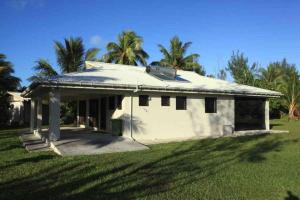 阿鲁坦加卡帕卡帕度假屋的一座小白色房子,在田野里种有棕榈树