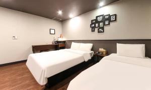 釜山No 25 Hotel Gwangan的配有白色床单的酒店客房内的两张床