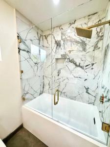 萨默兰SummerLillie #1的浴室配有白色浴缸和大理石墙。