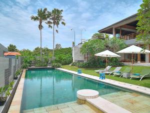金巴兰Villa Aiko的房屋旁的游泳池配有椅子和遮阳伞