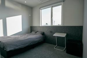 NEW HUMBER的一间卧室配有一张床、一张桌子和两个窗户