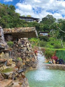 圣弗朗西斯科Natubri Ecohotel Habitacion VIP的花园内的瀑布,设有石墙