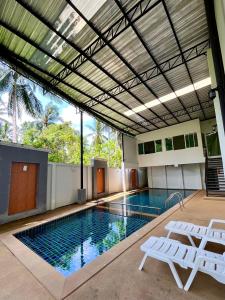 Ban Khlong HaengHidayah Condotel,Ao-nang, Krabi的一个带两把白色椅子的游泳池和一个游泳池