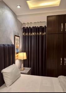 沙迦1 bed apartment available in Al nadd的一间卧室配有黑色窗帘、一张床和一盏灯