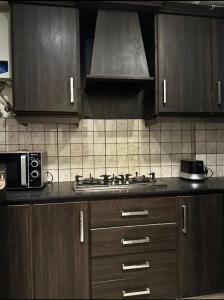 沙迦1 bed apartment available in Al nadd的厨房配有木制橱柜和炉灶烤箱。