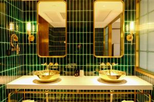 上海欣寓酒店(上海交通大学新华路店)的绿色瓷砖浴室设有两个水槽和镜子