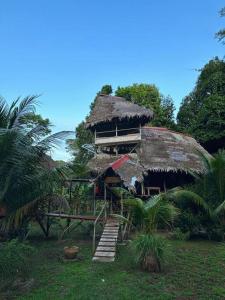 普卡尔帕Jungle Lodge with lookout tower的茅草屋顶和楼梯的房子