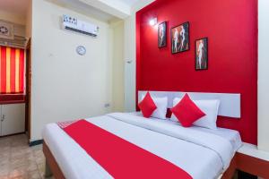 DewāsHotel Santushti的一间卧室设有红色的墙壁和一张带红色枕头的床