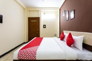 DewāsHotel Santushti的一间卧室配有一张带红色枕头的大床