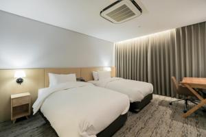 仁川市Aank Hotel Incheon Guwol的酒店客房配有两张床和一张书桌