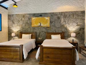 GinigathenaArsulana Eco Lodge & Spa的石墙客房的两张床
