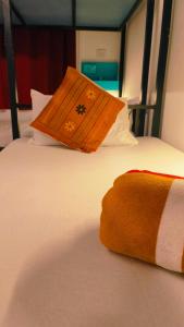 阿姆波尔Mitra Hostel的床上有一个橙色枕头