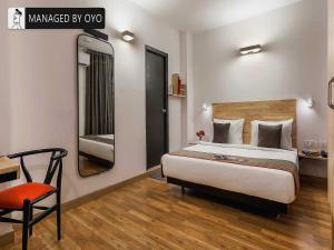 新德里Townhouse Greater Kailash Near Kailash Colony Metro Station的一间卧室配有一张床、一把椅子和镜子