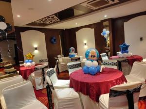 比拉斯布尔Hotel Vinayak Palace Telipara的一间设有两张桌子、白色椅子和气球的房间