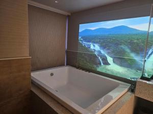 孟买Dragonfly Hotel- The Art Hotel的带浴缸的浴室,享有河景