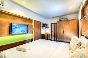 拉威海滩普吉岛标题精品公寓的卧室配有一张床,墙上配有电视。
