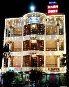 比拉斯布尔Hotel Shubh Shree Bilaspur的一座有灯的建筑,前面有标志
