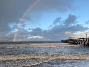 滨海吕克Le Nid douillet proche de la mer. La clef des paons的海面上的彩虹,带有码头和波浪