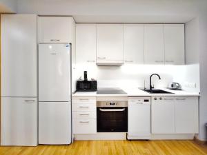 特拉萨Moderno apartamento tipo loft en Terrassa centro的厨房配有白色橱柜和冰箱。
