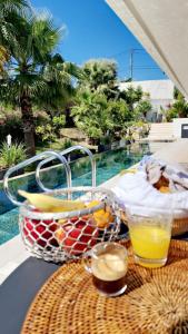 尼斯COTTAGE MARIN avec VUE MER的游泳池畔的桌子上放着一篮水果和饮料