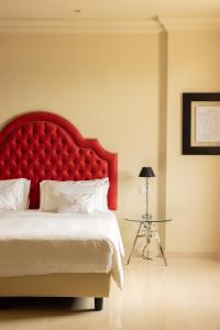 马泰拉Alvino Relais Mulino Contemporaneo的一间卧室配有红色的大床头板和一张桌子