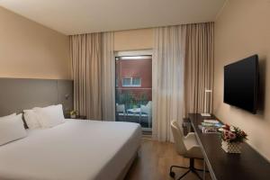奥里奥阿塞里奥NH欧瑞欧阿尔赛瑞欧酒店的配有一张床、一张书桌和一扇窗户的酒店客房