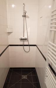 SwalmenHouterhoeve的白色瓷砖浴室内带软管的淋浴