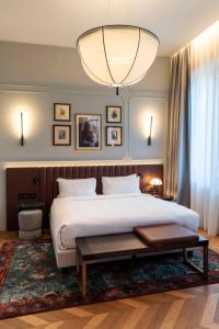 米兰Radisson Collection Hotel, Palazzo Touring Club Milan的一间卧室配有一张大床和一个大型吊灯。