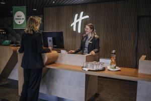 吕贝克Holiday Inn Lübeck, an IHG Hotel的两个妇女在商店的现金登记册上登记