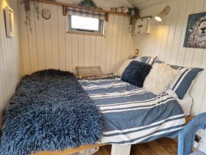 灵伍德Dolly at Lowlands的一张带蓝色和白色毯子及枕头的床