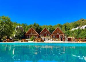 MayrūbāWood Hills Hotel & Resort的池边的一排小屋