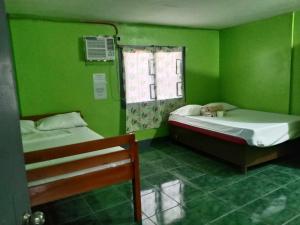 巴旺Bella's Beach Resort (A)的绿色的客房设有两张床和窗户。