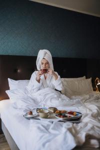 吕贝克Holiday Inn Lübeck, an IHG Hotel的躺在床上吃一盘食物的女人